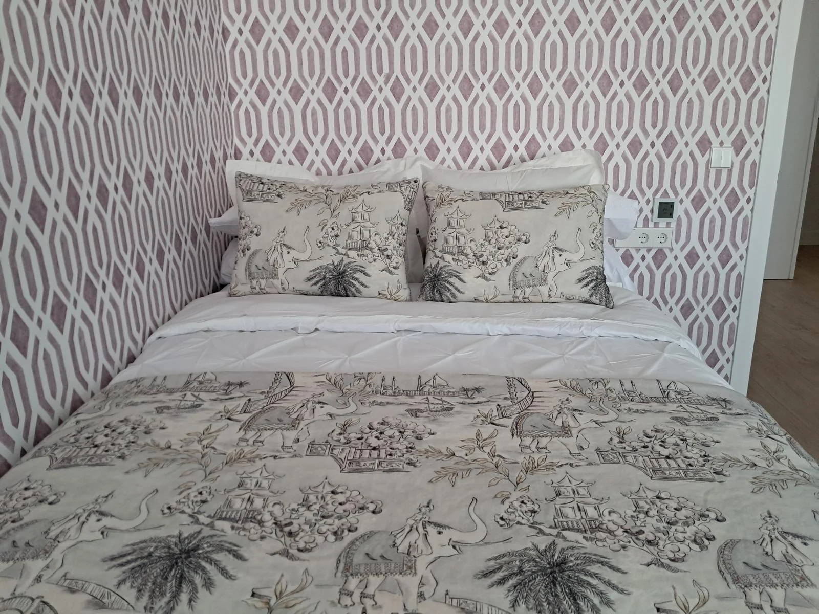 Dormitorio con papel pintado geométrico y textiles estampados.