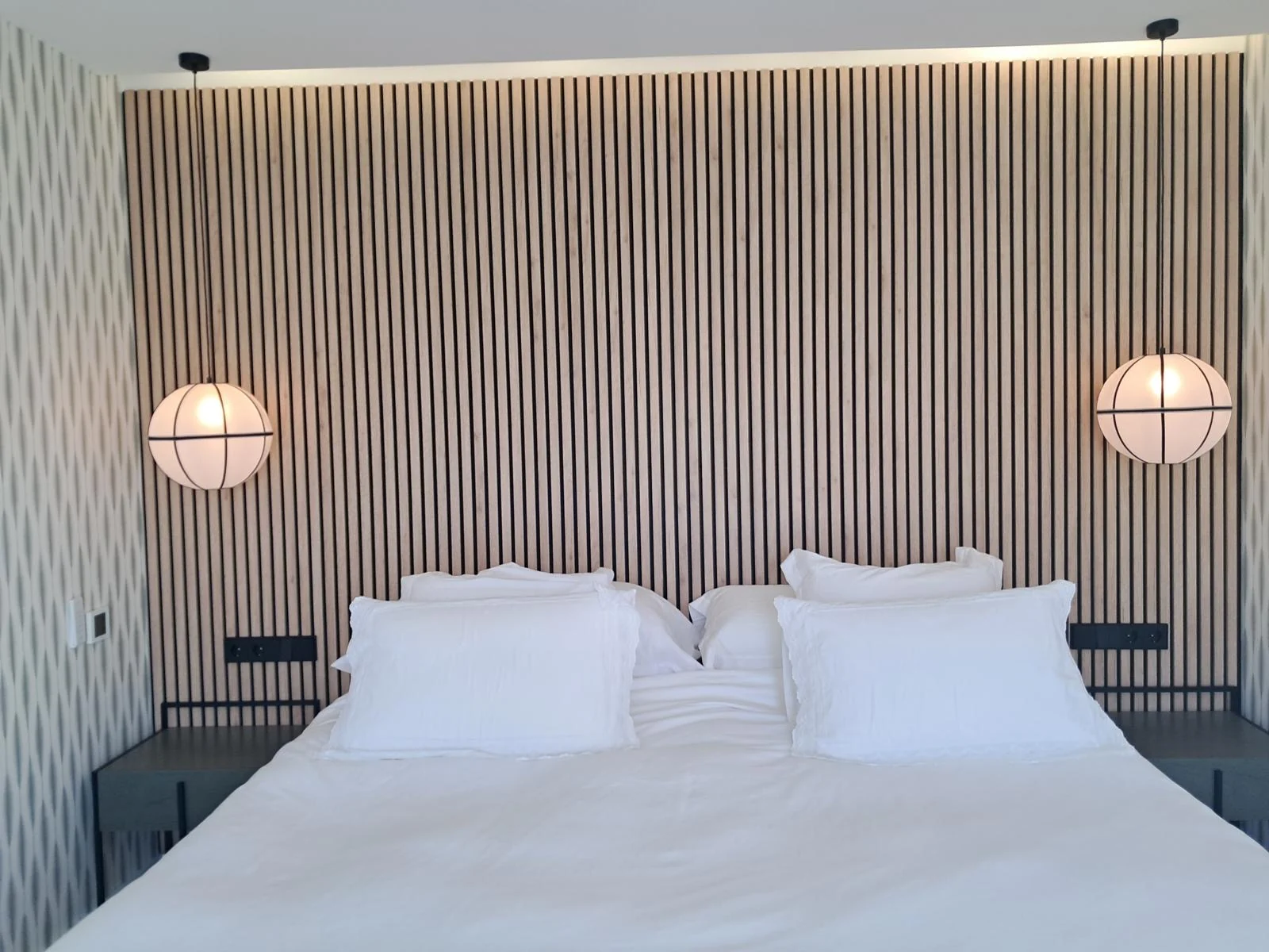 Dormitorio contemporáneo con lamas de madera e iluminación colgante.