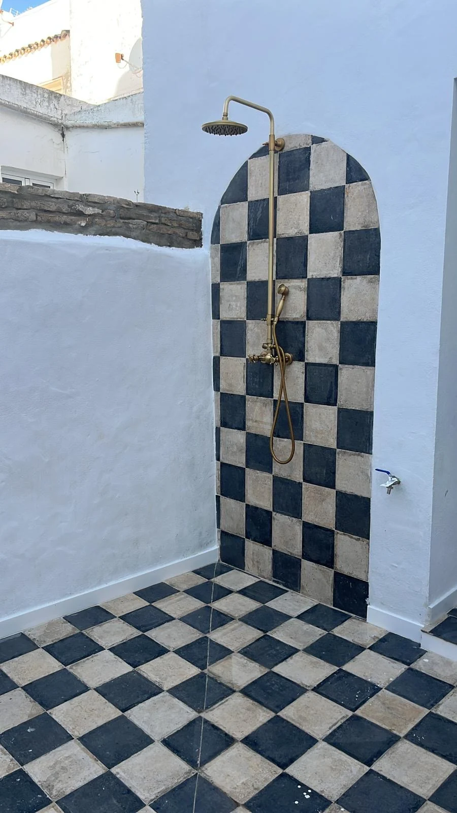 Patio exterior con revestimiento ajedrezado en blanco y azul.